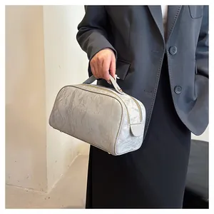 Detail shot of a silver textured cosmetic bag held by hand, showcasing chic design