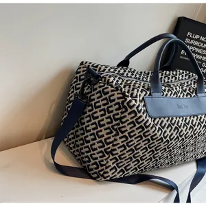 Vue détaillée d'un sac de voyage à motif géométrique avec poignées en cuir bleu