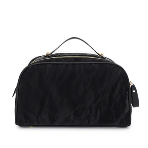 Detailed front view of a black crinkled texture makeup bag with gold metal zippers and handle