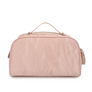 Detailed side view of light pink makeup bag showing crinkled texture and top handle