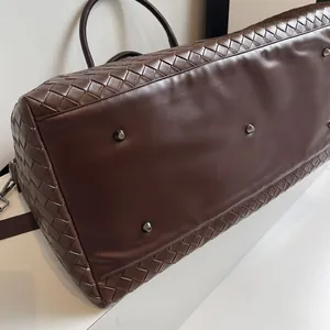 Detailed view of the smooth leather base and woven texture on a brown travel duffle bag
