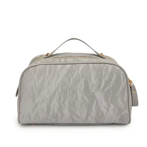 Close-up detail of silver grey cosmetic bag with crinkle texture and gold hardware
