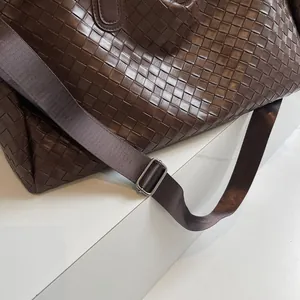 Close-up of a stylish brown woven travel bag showing the adjustable shoulder strap