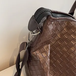 Macro view of brown woven faux leather travel bag showing texture and metal zipper