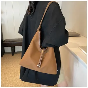 Minimalist large brown tote bag worn over the shoulder of a model in a black jacket
