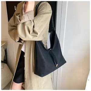 Detail view of a minimalist black large-capacity tote bag worn with a trench coat