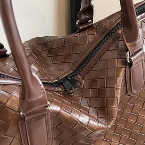 Detail of brown woven travel bag showing black double zipper and texture