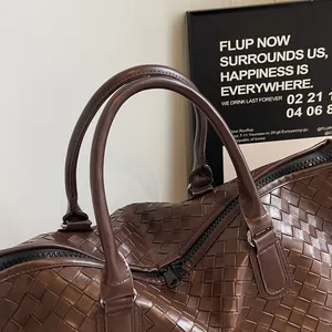 Macro view showing the detailed brown woven texture and handles of a travel duffel bag.