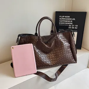 Detailed view of the large brown woven travel duffel bag with a pink tablet for scale