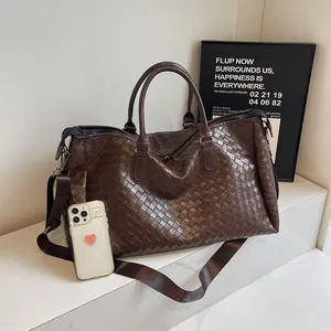 Detailed view of the large brown woven duffel bag with handles and a shoulder strap