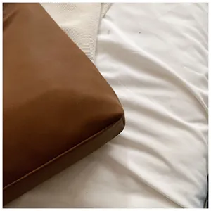 Close-up showing the precise stitching and corner detail of a brown minimalist leather tote bag