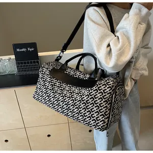 Grand sac de voyage à motifs géométriques pour femmes, porté à l'épaule par un mannequin.