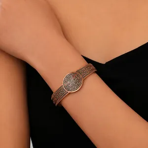 Nahaufnahme eines Vintage-Kupferarmreifs mit keltischen Knoten-Gravuren am Handgelenk