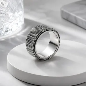 Close-up of a silver stainless steel mesh ring featuring a rotatable textured outer band.