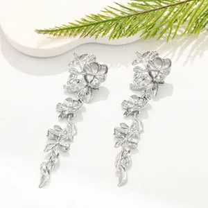 Close-up macro detail of silver floral drop earrings with intricate metal petal textures