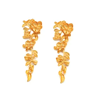 Detailed view of long gold metallic earrings featuring intricate flower and leaf patterns