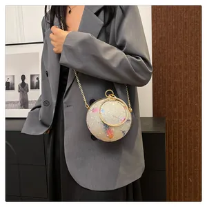 Nahaufnahme einer runden Abendtasche mit Federprint und goldener Kette als Detail.