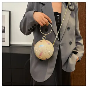 Detailansicht einer runden Abendclutch mit bunten Federdrucken und Metallringgriff