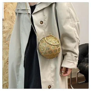Detail einer goldenen kugelförmigen Abendtasche mit Kettenriemen an einem Trenchcoat