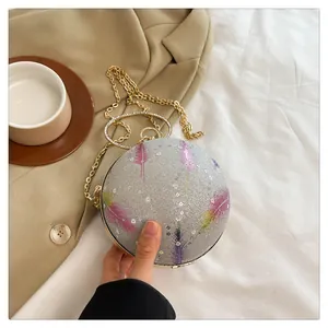 Detailansicht einer kugelförmigen Abendtasche mit Silberglitzer und bunten Federmustern