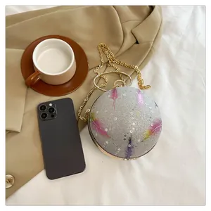 Detailansicht einer silbernen Kugeltasche mit Federprint und goldener Kette für den Abend.