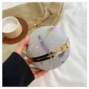 Nahaufnahme einer kugelförmigen silbernen Glitzer-Abendtasche mit bunten Federdrucken