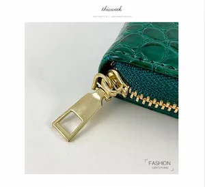 Nahaufnahme des eleganten goldenen Reißverschlusses an grüner Krokodil-Geldbörse