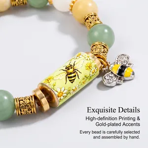 Macro view of a gold-plated bee charm bracelet with colorful beads and daisy prints.