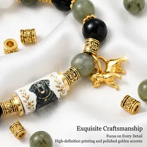 Close-up of golden dog charm and floral engraved beads on a stone bracelet
