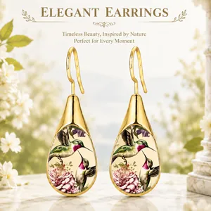 Detailed view of gold teardrop earrings featuring nature-inspired hummingbird pattern