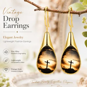 Vintage gold-tone teardrop earrings with cross sunset detail shown in a natural setting