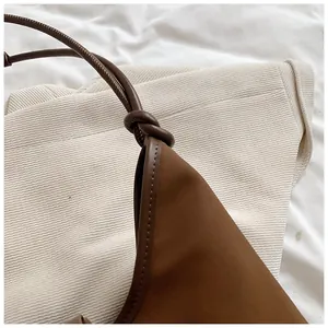Detail of brown leather tote bag showing the unique strap knot and fine stitching work.
