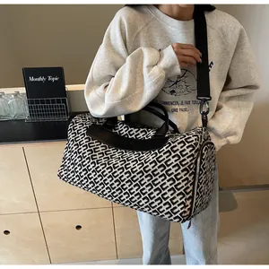 Gros plan d'un sac de voyage élégant à motif géométrique porté par un mannequin.