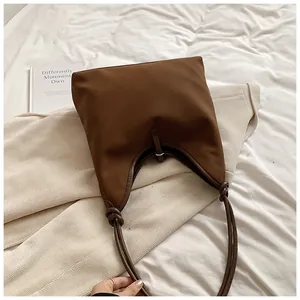 Detail view of a brown minimalist large capacity tote bag with unique knot handle design