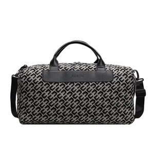 Détail d'un grand sac de voyage avec motif géométrique noir et poignées en cuir.