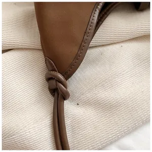 Detail shot of the brown leather tote bag featuring a knotted strap and fine stitching