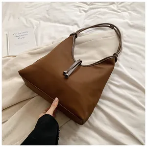 Detailed shot of brown minimalist tote bag featuring knotted straps and metal bead accents