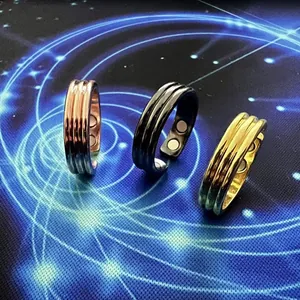 Detalle de tres anillos magnéticos en oro, negro y oro rosa sobre fondo azulado