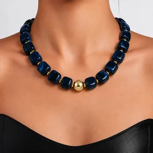 Detailed close-up of navy blue acrylic bead necklace with a central gold sphere bead
