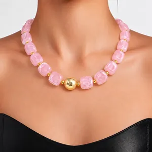 Macro detail of a fashion necklace with pink marbled acrylic beads and gold spheres