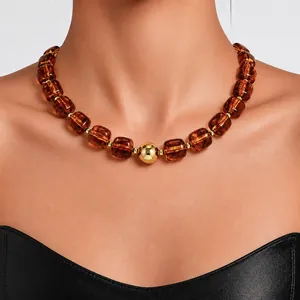 Close-up of amber acrylic beaded necklace with a central gold sphere on a model.