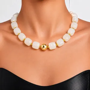 Detail of acrylic chunky necklace with white beads and large gold centerpiece bead