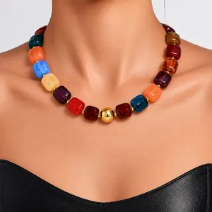 Close-up of colorful acrylic bead necklace with gold ball on model's neck