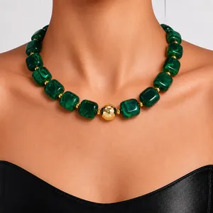 Detailed close-up of a green marble acrylic bead necklace with gold accents on a model