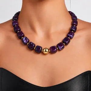 Close-up detail of a purple marble acrylic beaded necklace with a central gold bead