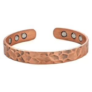 Macro shot of a vintage hammered copper cuff bracelet with embedded healing magnets.