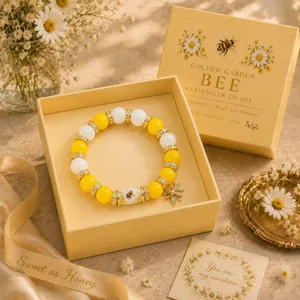 Detailed view of a handmade yellow and white beaded bee bracelet in its premium gift box