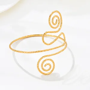 Detalle del patrón de espiral dorado texturizado en el brazalete.
