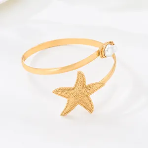 Vista detallada de un brazalete de brazo dorado con estrella de mar y perla