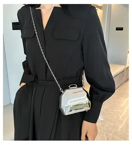 Stijlvolle zilveren metallic mini-avondtas met ketting, gedragen over een zwarte jurk.
